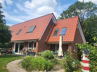 Backsteinhaus nach Dachsanierung mit rotem Ziegeldach und mehreren Dachfenstern