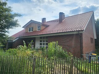 Gartenansicht eines Backsteinhauses mit saniertem roten Ziegeldach