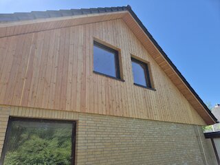 Neu verkleideter Giebel aus senkrechtem Holz an einem Backsteinhaus