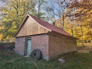 Saniertes Nebengebäude aus Backstein mit Holzgiebel und rotem Metalldach