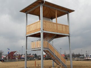 Zweistöckiger Aussichtsturm aus Holz mit überdachten Plattformen und Außentreppe