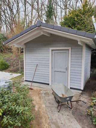 Kleines grau gestrichenes Gartenhaus aus Holz während der Fertigstellung