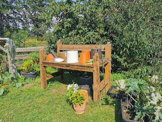 Handgefertigter Pflanztisch aus Holz mit Ablageflächen in einem Garten