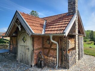 Rustikales Gartenhaus aus Holz und Backstein mit angebautem Brennholzlager