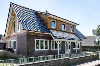 Saniertes Wohnhaus mit Dachgaube und weißem Holzvorbau