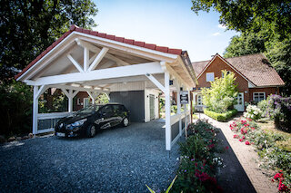 Weißer Holzcarport mit Satteldach und abgestelltem Auto