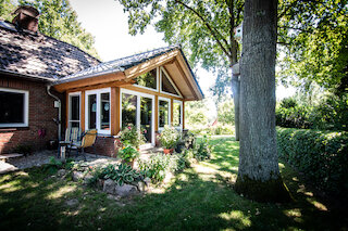 Glasreicher Holzanbau mit überdachter Terrasse im Garten