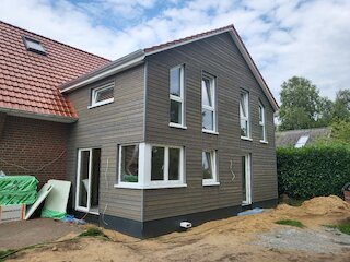 Zweigeschossiger Holzanbau mit grauer Fassadenverkleidung