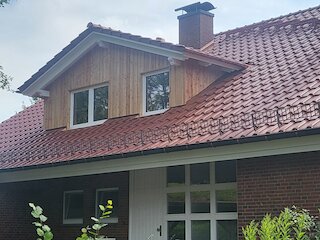 Dachgaube mit senkrechter Holzverkleidung und zwei Fenstern