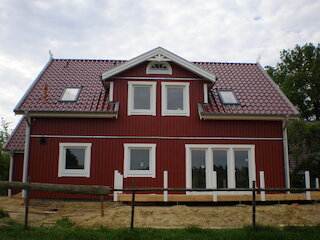 Rotes Holzhaus mit breiter Gaube und mehreren Fenstern