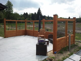 Holzterrasse mit Sichtschutz aus Glas und Holzrahmen
