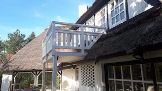 Kleiner Holzbalkon an einem Haus mit Reetdach