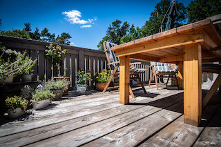Holzterrasse mit Sitzplatz und bepflanztem Geländer