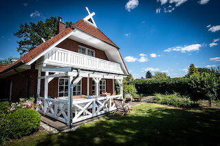 Wohnhaus mit weißem Balkon und überdachter Holzterrasse