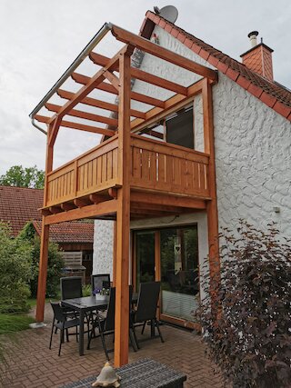 Zweigeschossige Holzbalkon-Konstruktion mit transparenter Überdachung