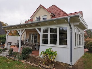 Weiße überdachte Veranda mit großen Fenstern und Sitzbereich