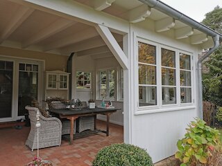 Sitzbereich unter einer weiß gestrichenen Terrassenüberdachung