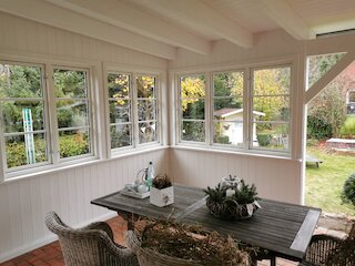 Innenansicht einer geschlossenen Veranda mit großen Fenstern